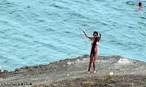 Fată jucăușă se dă în vânt, se zbenguiește goală pe plajă