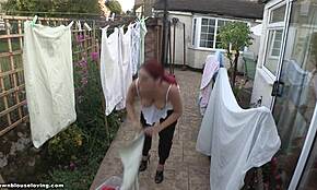 Upea punapäinen emäntä käy paljaalla ylävartalolla kotitöitä ulkona auringossa