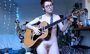 Pelirroja pequeña posando desnuda con tatuajes y gafas en webcam