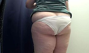 Милф с большой жопой в белых трусиках примеряет облегающие леггинсы в примерочной под близкой камерой