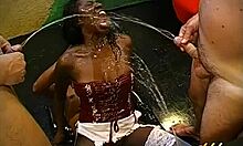 Ebony women on their knees engage in blowbang blowjobs, receiving golden showers and bukkake in dirty scenes.