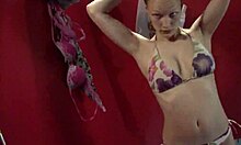 Emotionless blonde stares blankly while changing clothes in the room