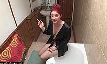 Half naked redhead almost loses her robe while smoking in bathroom.