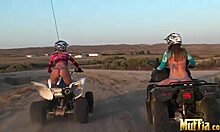 two blonde lesbians ride atvs half-naked, licking in desert