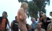 Russian blonde amateur strips naked outdoors, dancing with big natural tits and tan lines visible.