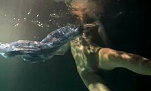 Russian brunette with big tits bounces underwater in the pool, showing her pussy