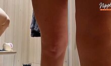 She tries on outfits and fingers her wet pussy in the changing room