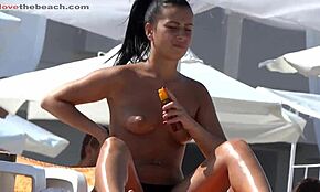 I saw this ponytailed brunette rubbing lotion topless on nudist beach